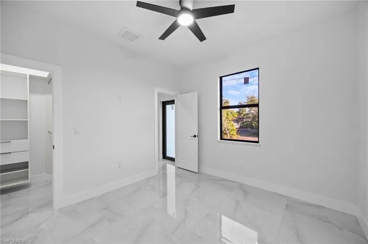 Unfurnished bedroom featuring baseboards, light marble finish flooring, and a ceiling fan