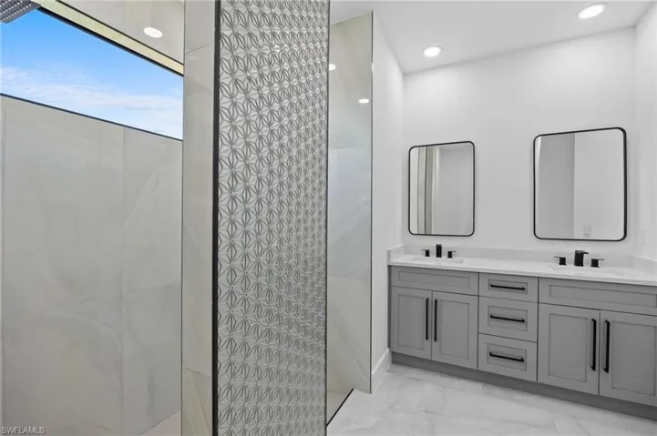 Bathroom with marble finish floors, a walk in shower, double vanity, and recessed lighting