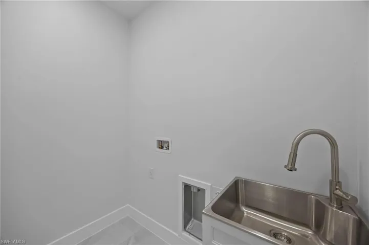Laundry room with baseboards, washer hookup, and marble look tiles