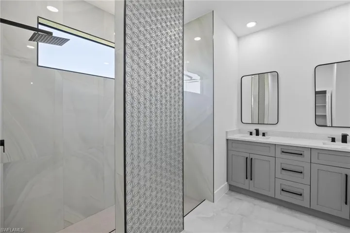 Full bath with marble finish flooring, walk in shower, and double vanity