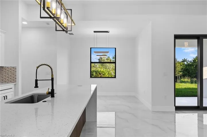 Kitchen with a sink, light stone countertops, plenty of natural light, pendant lighting, and recessed lighting