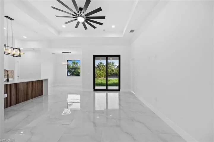 Unfurnished room featuring a raised ceiling, a chandelier, recessed lighting, ceiling fan, and baseboards