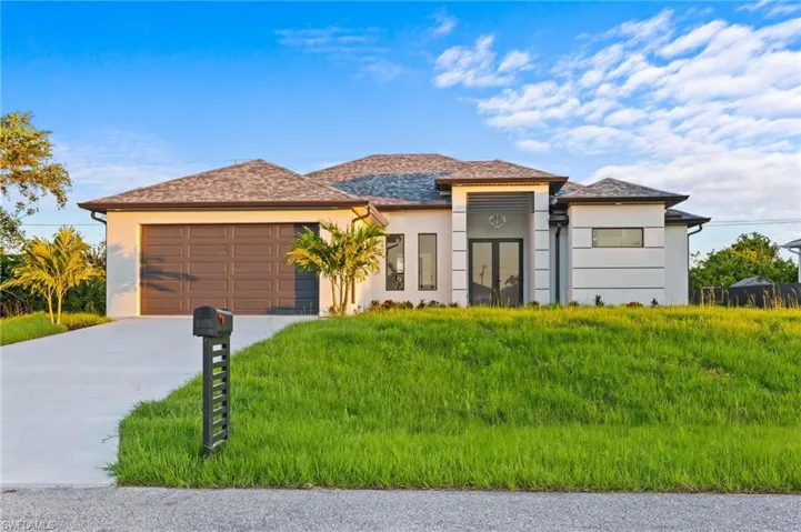 Prairie-style home with stucco siding, a garage, and driveway