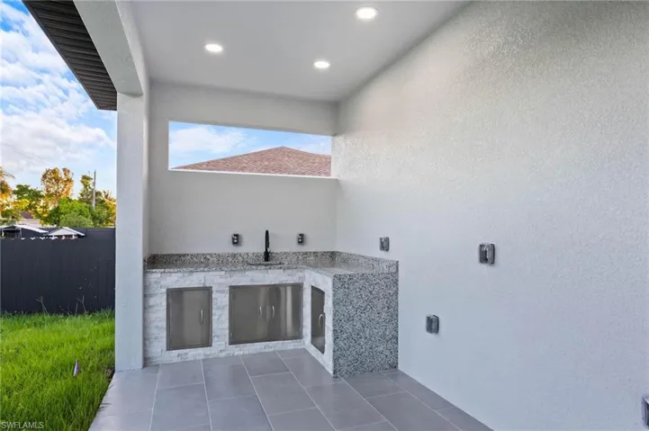 View of patio with an outdoor kitchen, a sink, and fence