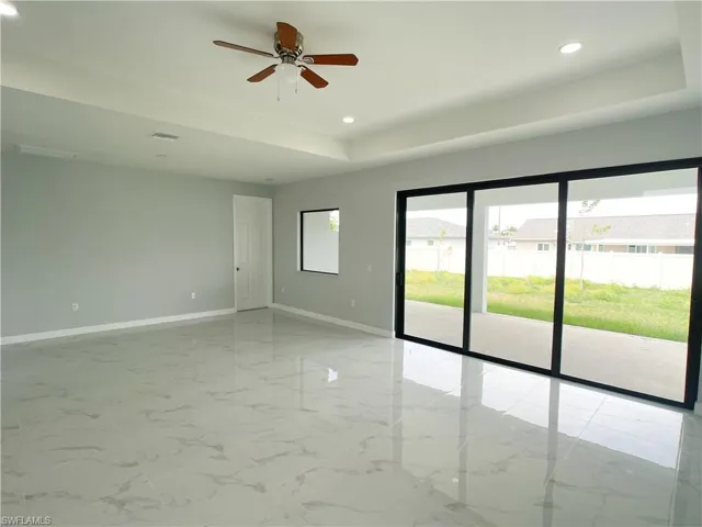 Empty room featuring recessed lighting, a tray ceiling, marble finish floor, and baseboards