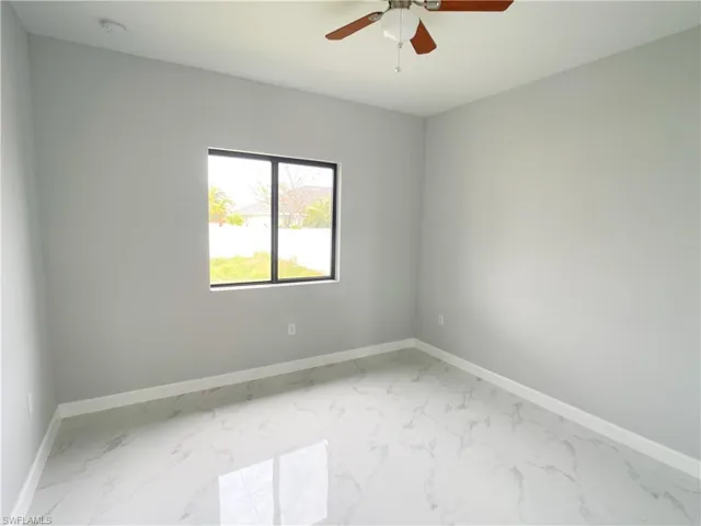 Empty room with baseboards, marble finish floor, and ceiling fan
