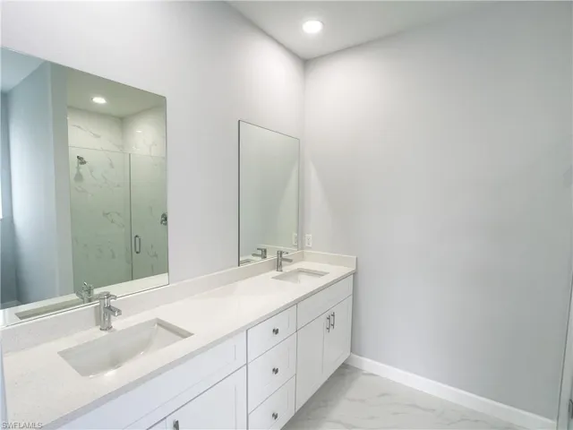 Bathroom with marble finish floor, a sink, baseboards, and a marble finish shower