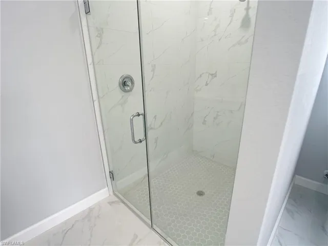 Bathroom with marble finish floor, baseboards, and a stall shower