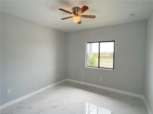 Spare room with baseboards, marble finish floor, and ceiling fan