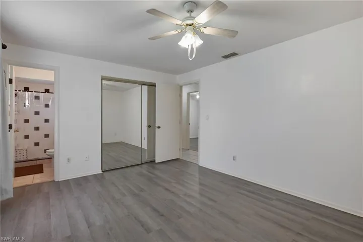 Unfurnished bedroom with hardwood / wood-style flooring, ensuite bathroom, a closet, and ceiling fan