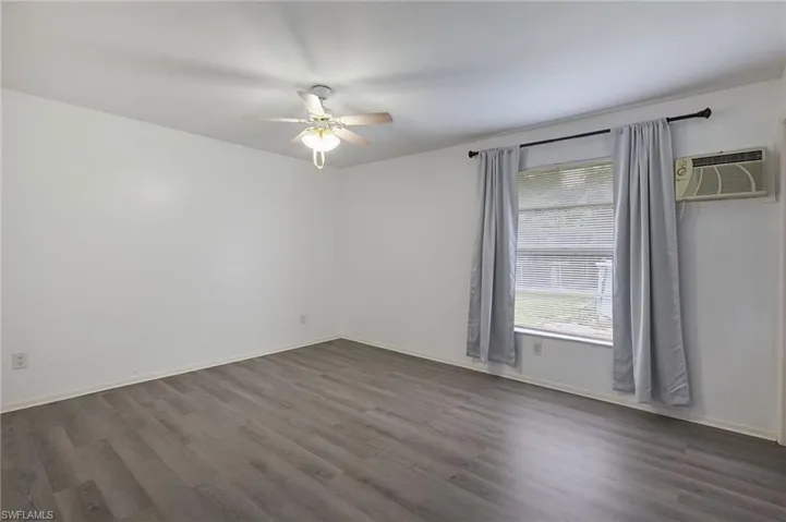 Spare room with hardwood / wood-style flooring, a wall mounted AC, and ceiling fan