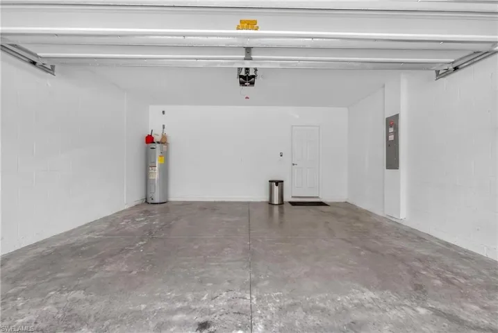 Spacious garage featuring concrete flooring, painted block walls, and a dedicated utility area