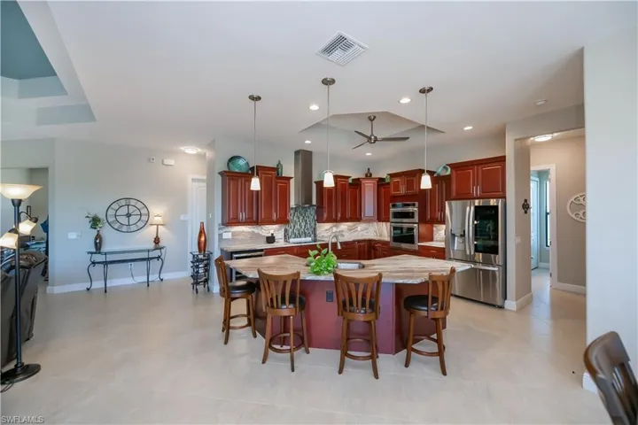 Kitchen with stainless steel fridge with ice dispenser,  and a massive island with sink