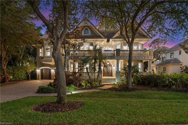 View of front of house with a yard, a garage, a balcony, stucco siding, and decorative driveway