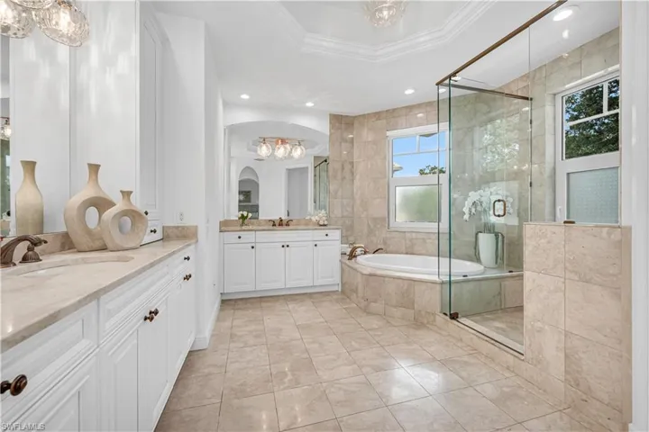 Bathroom with a chandelier, a shower stall, a sink, and crown molding