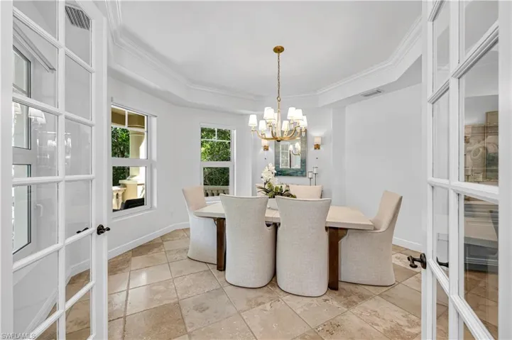 Dining room with visible vents, ornamental molding, a chandelier, a tray ceiling, and french doors