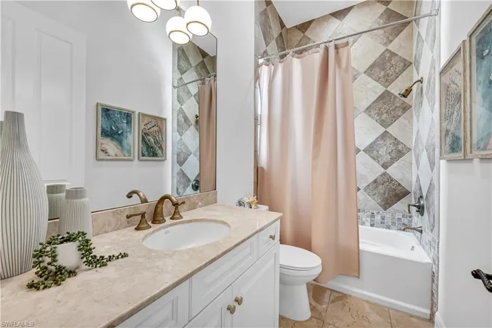 Bathroom with shower / bath combination with curtain, vanity, and toilet