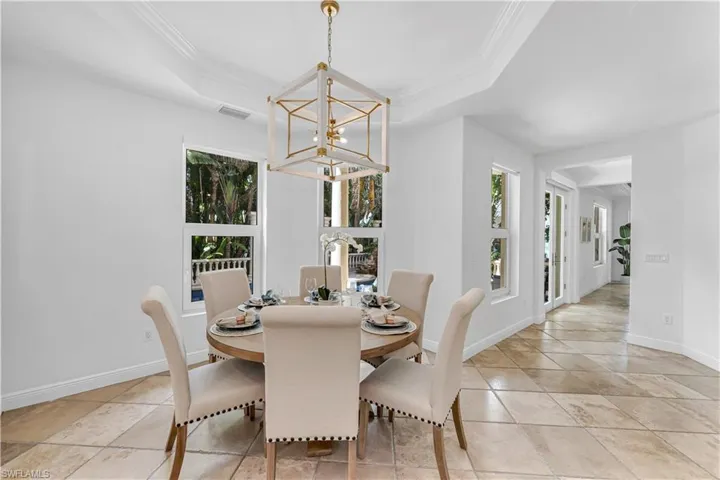 Dining space with crown molding, a tray ceiling, a notable chandelier, and visible vents