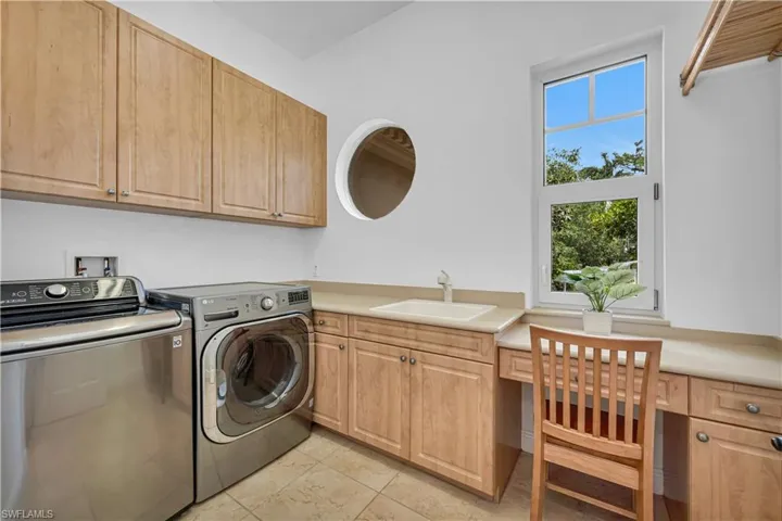 Washroom with washer and clothes dryer, a sink, and cabinet space