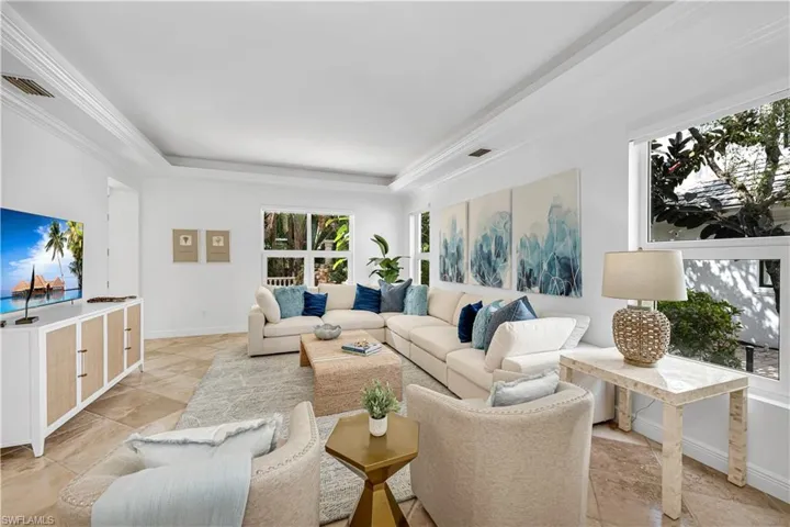 Living area with a raised ceiling, baseboards, ornamental molding, and visible vents