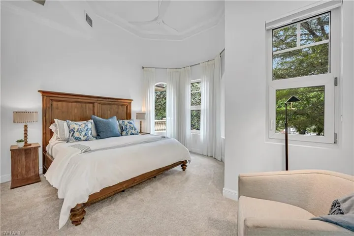 Bedroom with a raised ceiling, light carpet, baseboards, and visible vents
