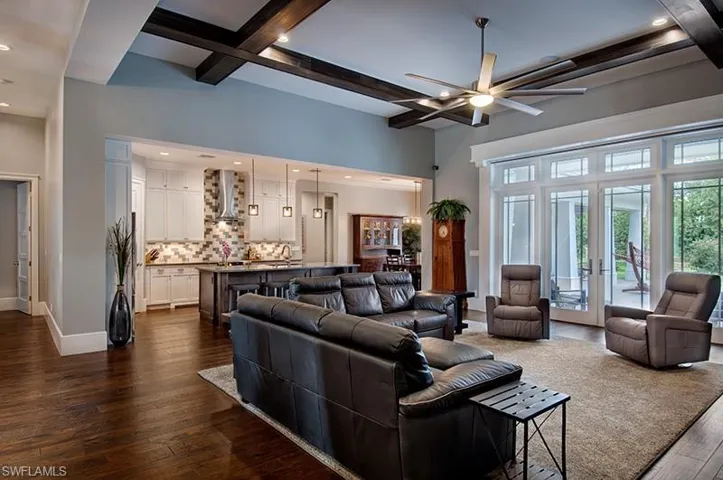 Living room featuring a towering ceiling, french doors, dark hardwood / wood-style floors, ceiling fan, and beam ceiling