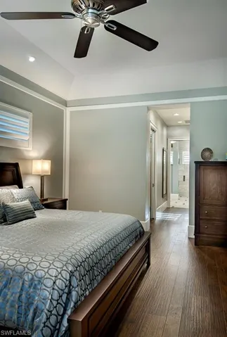 Bedroom with hardwood / wood-style flooring, connected bathroom, vaulted ceiling, and ceiling fan