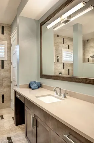 Bathroom featuring vanity, a shower, tile walls, and tile patterned flooring
