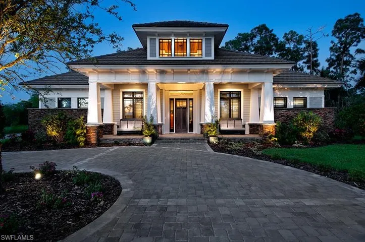 View of front of home featuring covered porch, stone siding, and decorative driveway