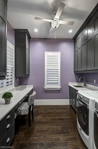 Laundry area featuring cabinet space, dark wood-style floors, ceiling fan, washer and dryer, and a sink