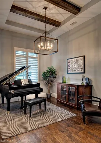 Misc room featuring hardwood / wood-style floors, beamed ceiling, and a notable chandelier