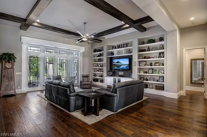 Living room with built in features, ceiling fan, beamed ceiling, and dark hardwood / wood-style flooring
