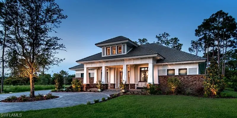 View of front of property featuring covered porch, stone siding, and a front lawn