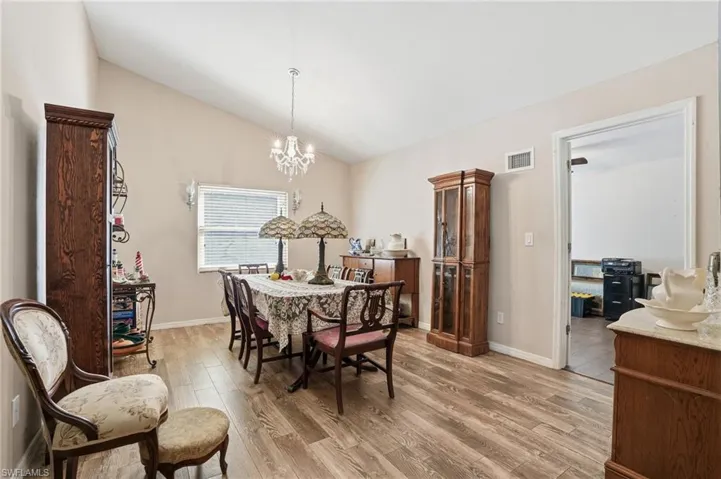 Dining area with light wood finished floors, vaulted ceiling, and hanging lights