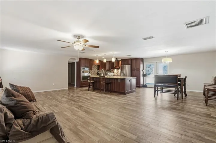 Living area with arched walkways, light wood-style flooring, and a ceiling fan