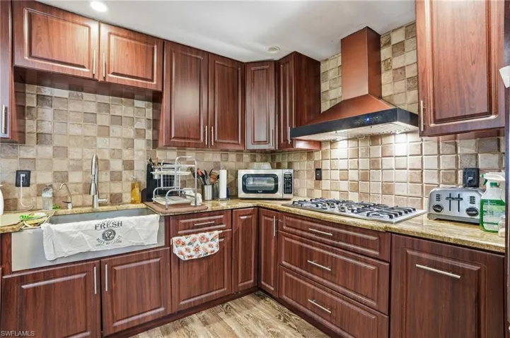 Kitchen featuring light stone countertops, backsplash, light wood-style floors, and stainless steel appliances