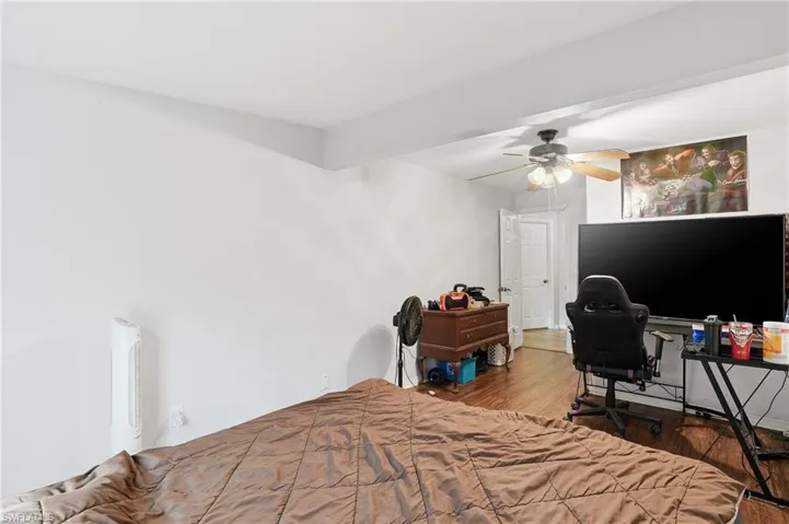 Bedroom with wood finished floors, a desk, and a ceiling fan