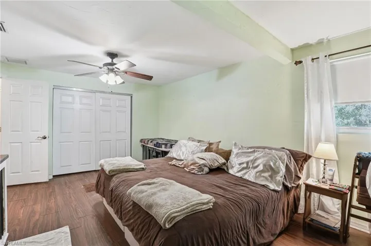 Bedroom with dark wood-style flooring, a closet, a ceiling fan, and beam ceiling