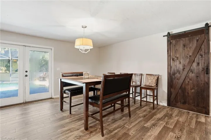 Dining area featuring a barn door, light wood finished floors, and french doors