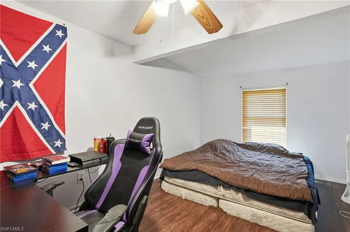 Bedroom featuring dark wood finished floors, ceiling fan, a desk, and beam ceiling