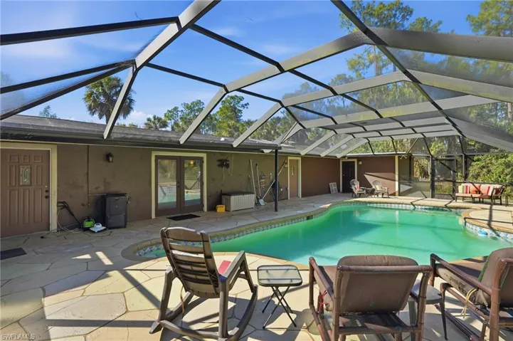 Swimming pool featuring french doors, glass enclosure, a patio, and a sunroom