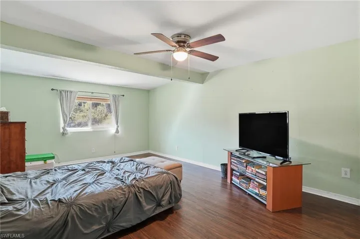 Bedroom with beamed ceiling, dark wood-style flooring, and ceiling fan