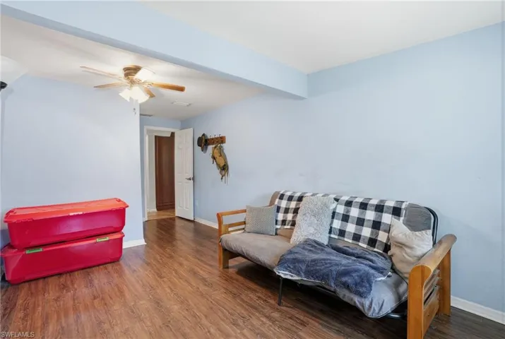 Living area with dark wood-style floors, beamed ceiling, and a ceiling fan