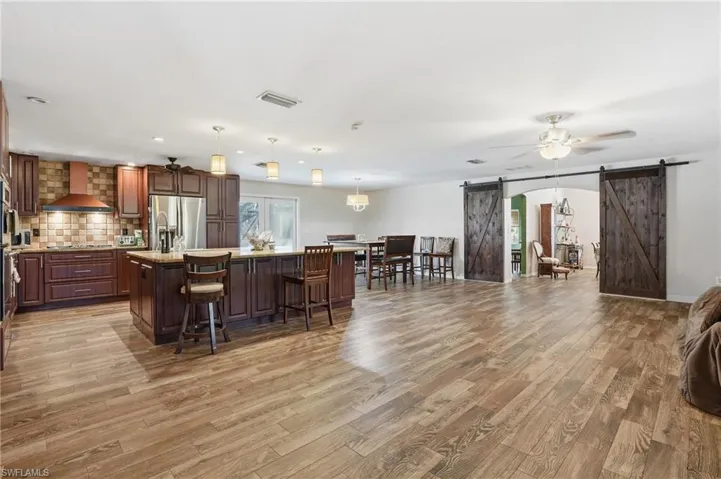 Kitchen featuring a barn door, open floor plan, a center island, hanging light fixtures, and a ceiling fan
