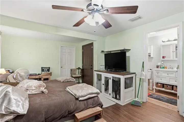 Bedroom with wood finished floors, ceiling fan, and ensuite bathroom