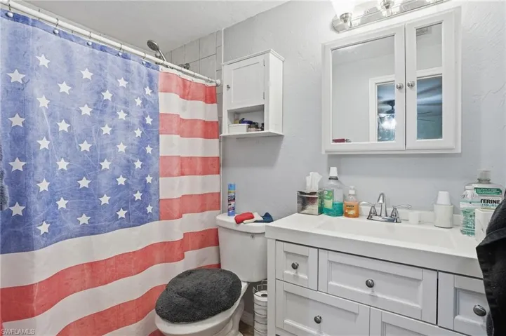 Bathroom with a shower with curtain, vanity, and a textured wall