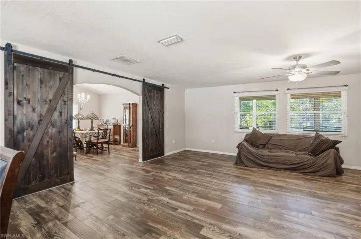 Sitting room with a barn door, arched walkways, and wood finished floors