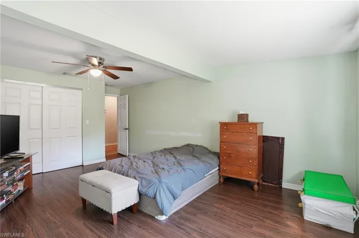 Bedroom featuring dark wood-style flooring, a closet, ceiling fan, and beamed ceiling