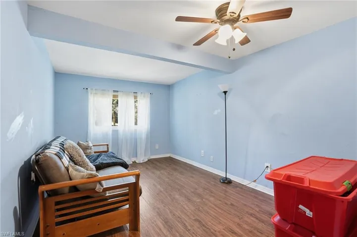 Living area with dark wood finished floors, beam ceiling, and a ceiling fan