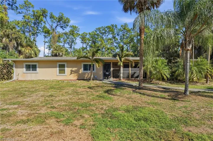 Back of property featuring a yard, stucco siding, and a sunroom